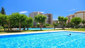 A swimming pool with clear blue water, surrounded by trees and buildings. - Nice family apartment close to PortAventura - UHC JEREZ APARTMENTS 158 (Salou)