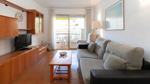 A modern living room with a sofa, TV, wooden cabinet, and a table with a decorative bowl. - Nice family apartment close to PortAventura - UHC JEREZ APARTMENTS 158 (Salou)