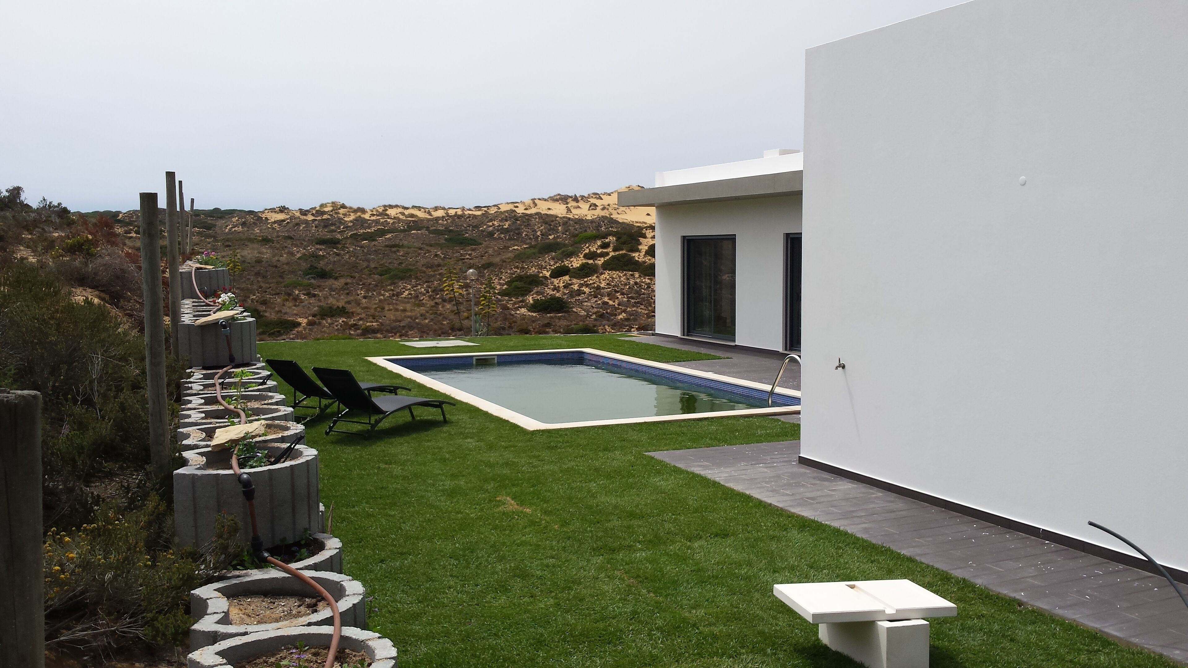 A modern outdoor pool area with a rectangular pool, surrounded by a well-maintained lawn and a stone pathway.
