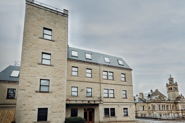 A multi-story building with a stone facade, multiple windows, and a bell tower.