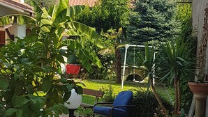 Un patio jardín con una silla azul, una escultura de pájaro blanco y un sendero de piedra.