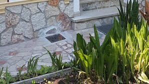 Entrada de un edificio con un arco decorativo, un camino de piedra y un pequeño jardín con plantas.