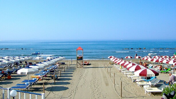 A beach with rows of sun umbrellas and lounge chairs, a lifeguard tower, and the ocean in the background. - Apartment Le Cannucce at the sea of Castiglione (Castiglione della Pescaia)