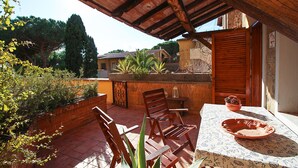 An outdoor patio with wooden furniture, a table with a patterned tablecloth, and a potted plant. - Apartment Le Cannucce at the sea of Castiglione (Castiglione della Pescaia)