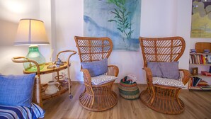 A room with two wicker chairs, a small table with a lamp, and a bookshelf. - Apartment Le Cannucce at the sea of Castiglione (Castiglione della Pescaia)