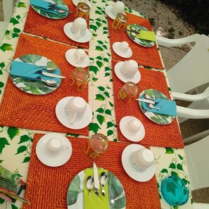 A table set with white plates, cups, and cutlery, arranged on a woven placemat with a green leaf pattern. - EDERA bed and breakfast (Porto Sant'Elpidio)