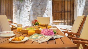 A wooden table set with breakfast items, including croissants, orange juice, and a newspaper. - Hedera Estate, Villa Hedera IV (Dubrovnik)