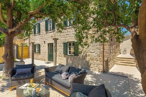 A stone building with a balcony, furnished with wicker furniture and a glass table. - Hedera Estate, Villa Hedera IV (Dubrovnik)