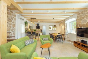 A spacious living area with a green sofa, a wooden coffee table, and a TV on a wooden stand. - Hedera Estate, Villa Hedera IV (Dubrovnik)