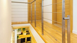 A modern staircase with a metal handrail, wooden steps, and a small dining area below. - Hedera Estate, Villa Hedera IV (Dubrovnik)