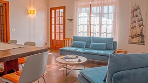 Ein Wohnzimmer mit einem blauen Sofa, einem Holzesstisch und einem runden Couchtisch.