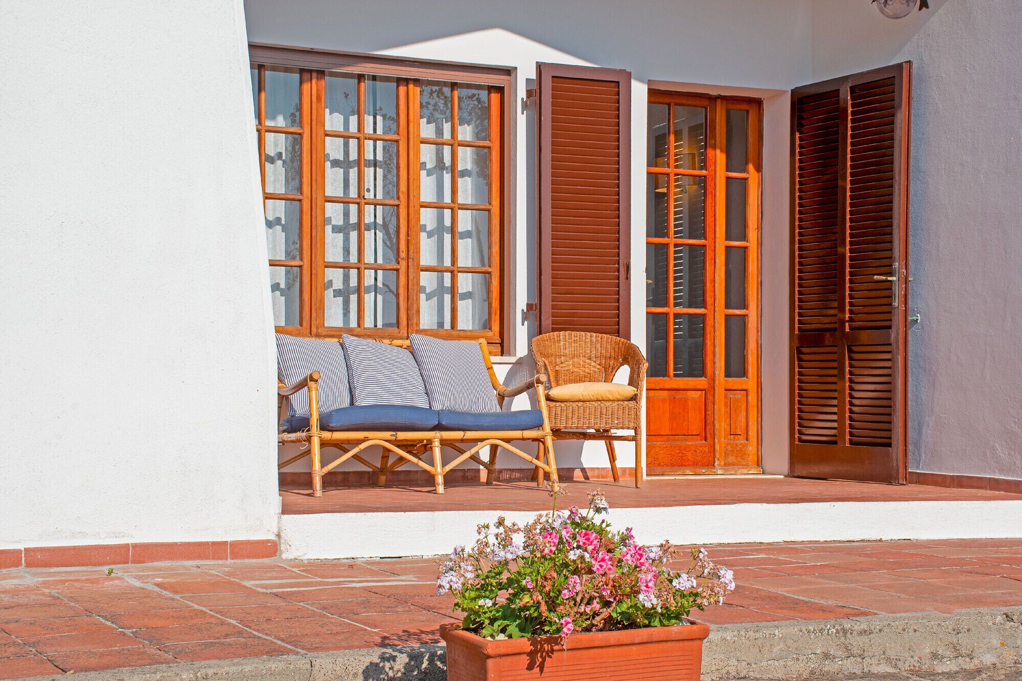 A covered outdoor seating area with wicker furniture and a flower planter.