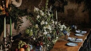 A long wooden table set with plates, glasses, and a centerpiece of white flowers.