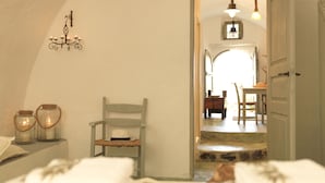 Een knus slaapkamer met een bed, een stoel en een nachtkastje met kaarsen.