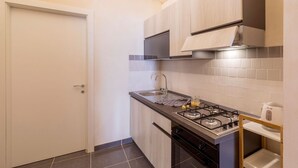 A modern kitchen with a gas stove, sink, and wooden cabinets. - Balbo 9A Apartment - Lecce Selection (Lecce)