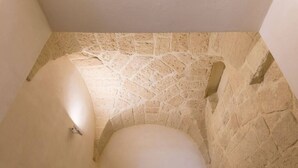 A bathroom with a stone wall, a white bathtub, and a corner sink. - Balbo 9A Apartment - Lecce Selection (Lecce)