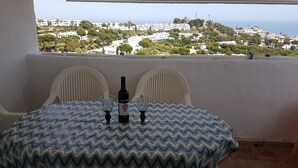 Ein Balkon mit Tisch für zwei Personen mit Blick auf eine Küstenstadt.