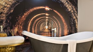 A modern bathroom with a bathtub, a mirror, and a decorative wall. - Manchester Hall (Manchester)