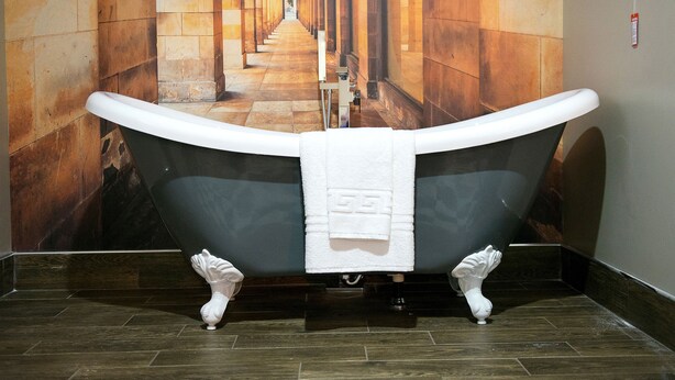 A bathtub in a hallway with a tiled floor and a mural of a corridor. - Manchester Hall (Manchester)