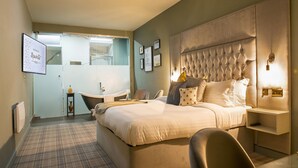 A hotel room with a large bed, a bedside table, a chair, a desk, and a mirror. - Manchester Hall (Manchester)