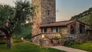 A stone house with a tiled roof, a brick chimney, and a paved pathway leading to the entrance.