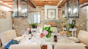 A dining area with a stone wall, wooden ceiling, and two hanging lanterns.
