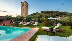 A pool area with lounge chairs and a stone tower in the background.
