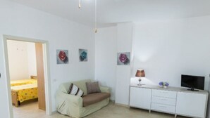 A small, well-lit room with a bed, a sofa, a TV, and a desk. - LAST MINUTE Torre Mozza - Apartment on the sea 21 (Torre Mozza, Lecce)
