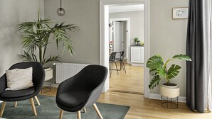 Un salon moderne avec deux fauteuils noirs, une plante en pot et une vue sur la salle à manger.