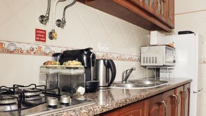Een keuken met een gasfornuis, een koffiezetapparaat, een magnetron en een koelkast.