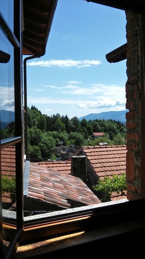 Experience the rustic charm of a traditional building amidst lush greenery and breathtaking mountain views.