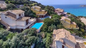 A coastal residential area with houses, a swimming pool, and a view of the sea.