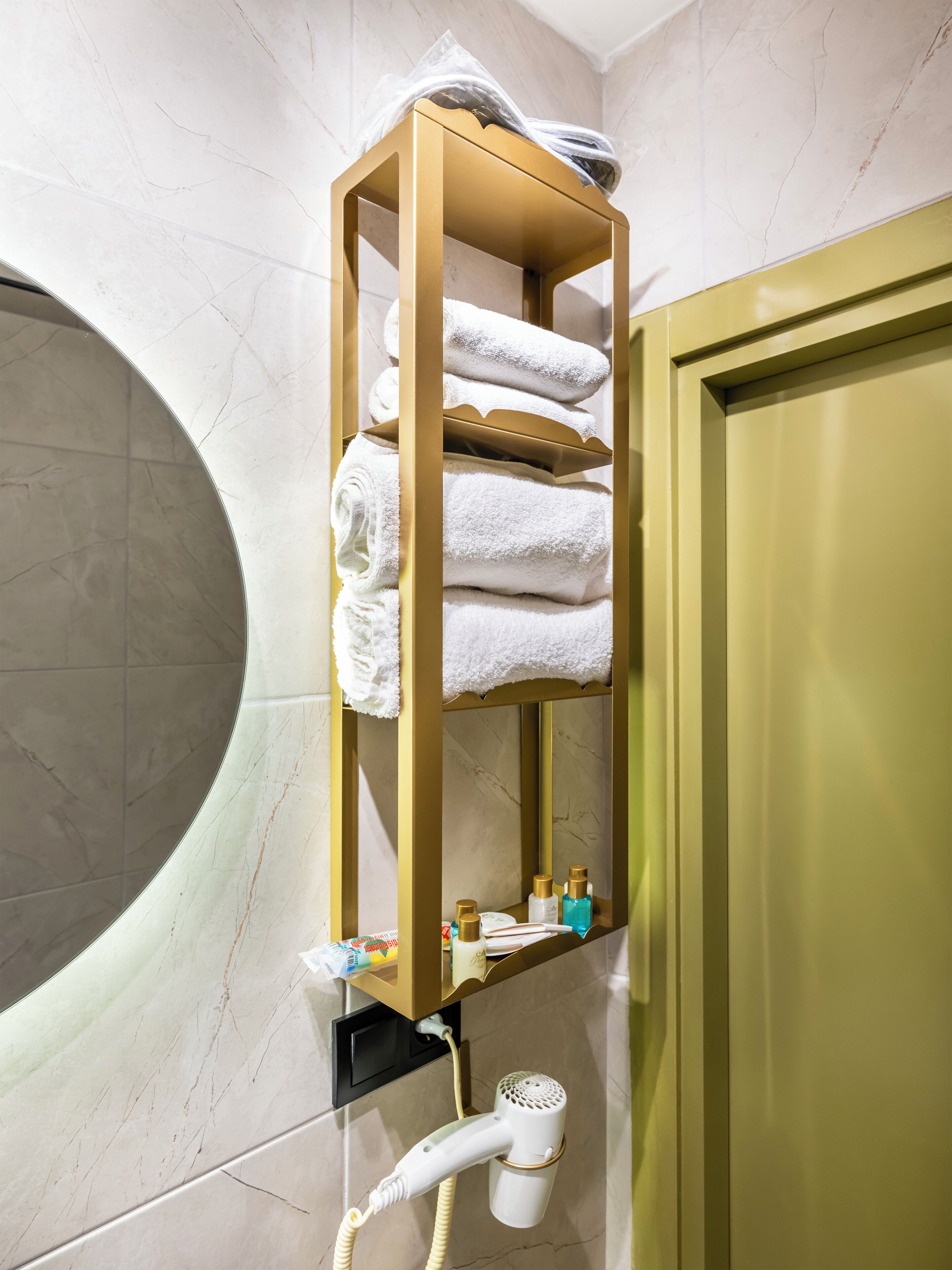 A bathroom with a towel rack, a hairdryer, and toiletries on a shelf.