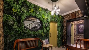 Une pièce avec un mur vert, un banc en bois, une table et un miroir.