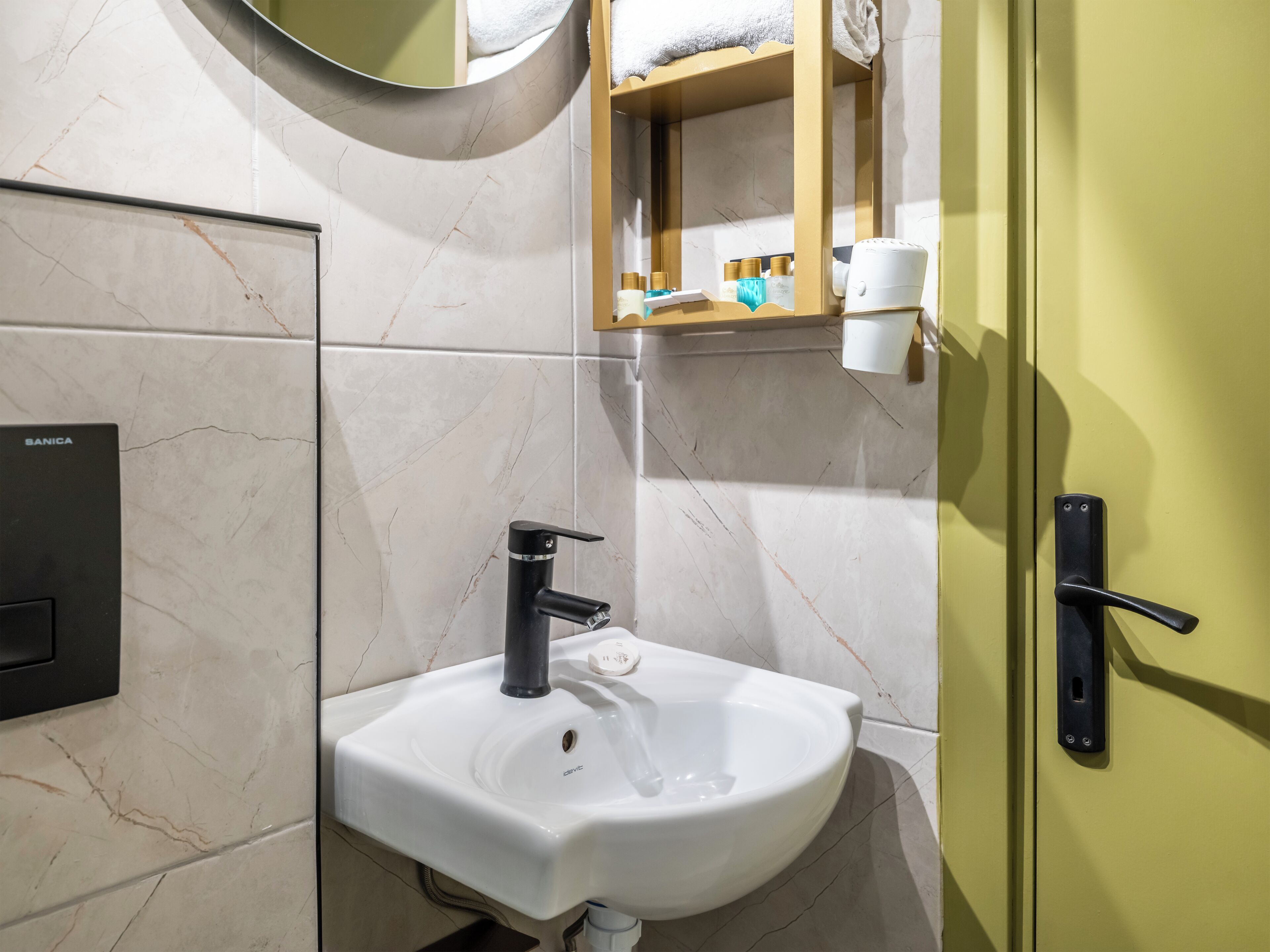 A bathroom with a white sink, a black faucet, a mirror, and a towel rack.