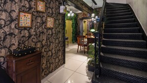 Un escalier menant à une salle à manger avec une table et des chaises, un buffet en bois et des tableaux encadrés accrochés au mur.
