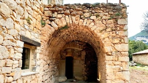 Un edifici de pedra amb una entrada apuntada i una finestra.