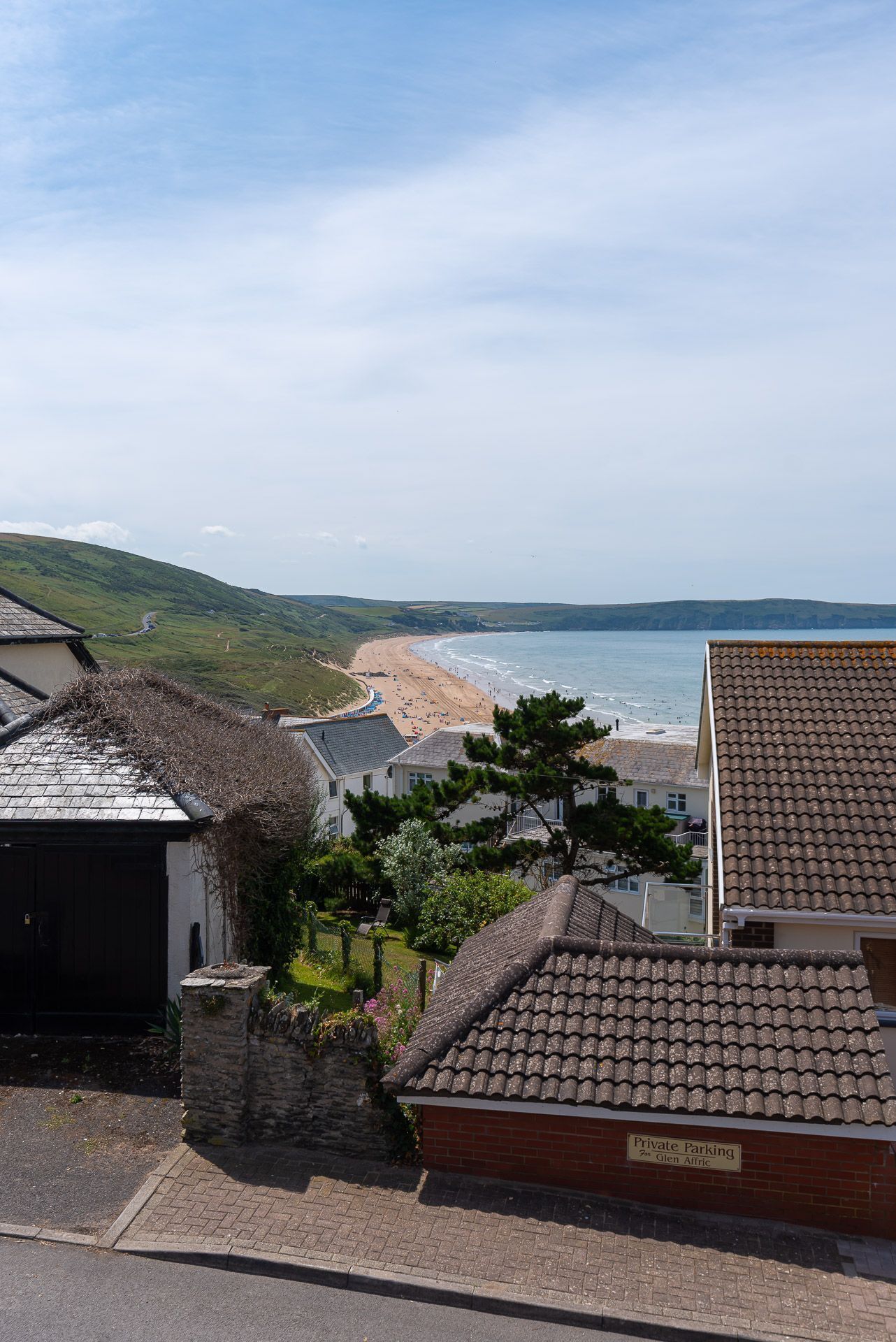 Eine Wohngegend an der Küste mit Blick auf den Strand, privatem Parkplatz und Häusern mit Ziegeldächern.