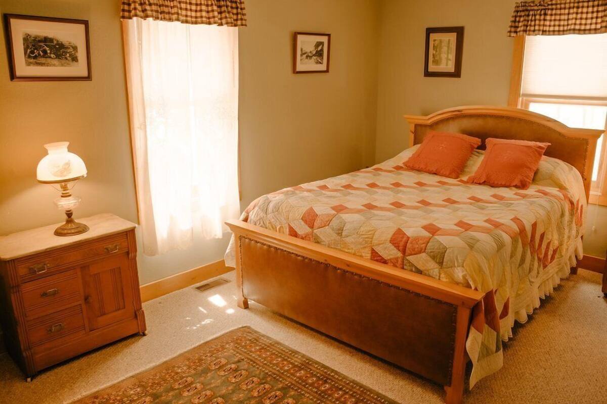 A bedroom with a wooden bed, a nightstand, a lamp, and a rug.