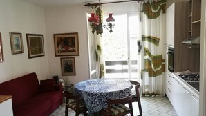 Un comedor acogedor con una mesa redonda y sillas, un sofá rojo y una zona de cocina con estufa.