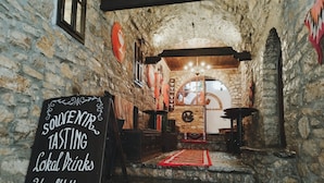 A stone-walled interior with a chalkboard sign advertising local drinks and healthy products. - Guva Mangalem (Berat)
