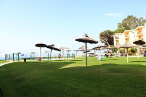 A poolside area with thatched umbrellas, a pool, and a building with balconies.