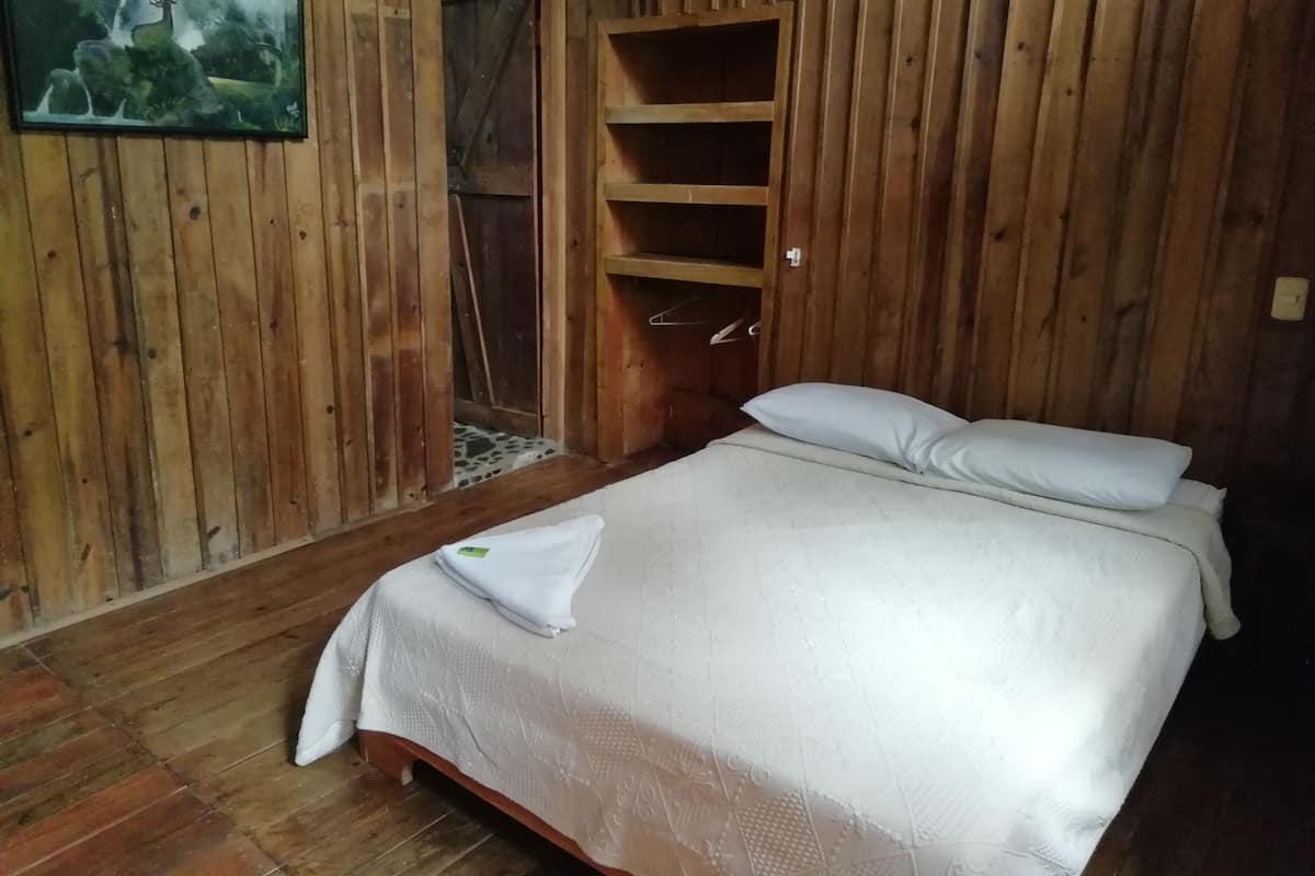 Um quarto de madeira com uma cama, um quadro e uma porta de madeira.