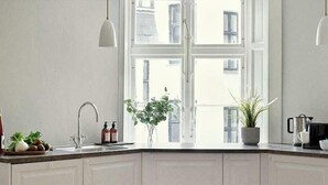 A fully equipped kitchen with white cabinets, a wooden countertop, and a window providing natural light.