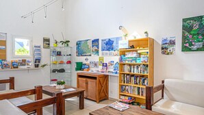 Et hyggeligt bibliotek med møbler i træ, reoler og et skrivebord med en computer.