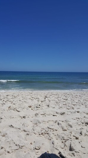 Ein sandiger Strand mit Fußspuren, die zum Wasser führen.