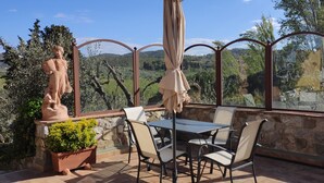 A patio with a table and chairs, a statue, and a view of the countryside. - Machiavelli Apartment (lastra a signa)
