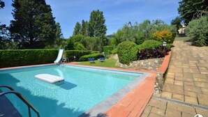 A rectangular swimming pool with a white floating platform, surrounded by a brick border. - Machiavelli Apartment (lastra a signa)