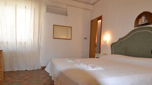 A hotel room with a single bed, a wooden dresser, a mirror, and a wall-mounted light fixture. - Agllipoli Penthouse 215 (Gallipoli)