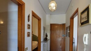 A hallway with a wooden door at the end, a radiator, and a telephone on the wall. - Agllipoli Penthouse 215 (Gallipoli)